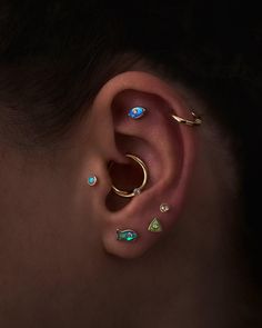 a woman wearing ear piercings with different colored stones on her ears and behind her ear