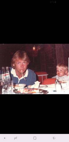 a man and child sitting at a table with food in front of them, eating