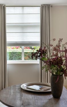 a vase filled with flowers sitting on top of a wooden table next to a window