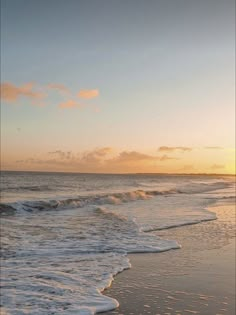 the sun is setting over the ocean with waves coming in