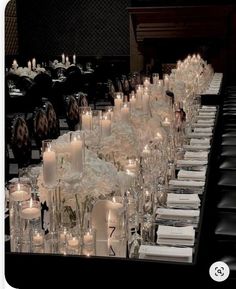 a long table is set with many candles and place settings for the guests to sit down