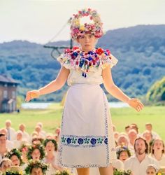 a woman standing on top of a field with lots of people in the back ground