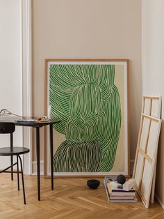 an art work is displayed in the corner of a room with two chairs and a table