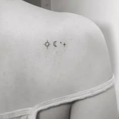 the back of a woman's shoulder with three stars and moon tattoos on it