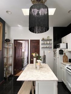 a kitchen with an island and chandelier hanging from the ceiling