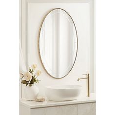 a white sink sitting under a round mirror