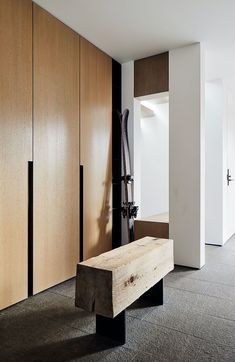 a wooden bench sitting in the middle of a room next to closets and doors