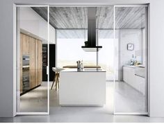 an open door leading to a kitchen and dining area with white walls, flooring and cabinets