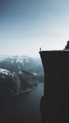 a person standing on the edge of a cliff looking out over a body of water