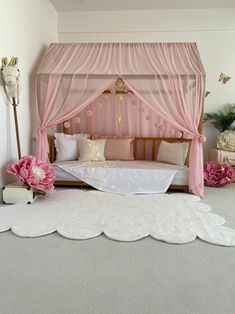 a bed with pink curtains and pillows in a room that has white carpet on the floor