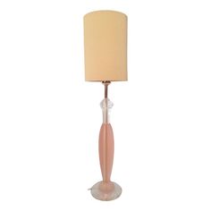 a pink lamp with a beige shade on it's base and a white lampshade