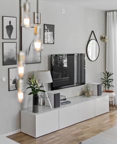 a living room with white furniture and pictures on the wall, including a flat screen tv