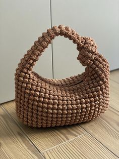 a crocheted purse sitting on top of a wooden floor next to a wall