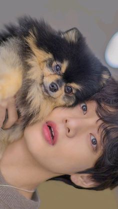 a woman is holding a small dog on her shoulder while she looks at the camera