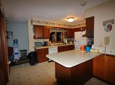 a kitchen with wooden cabinets and white counter tops in front of a refrigerator freezer