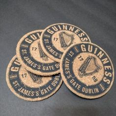 four guinness cork coasters sitting on top of a black tablecloth covered flooring