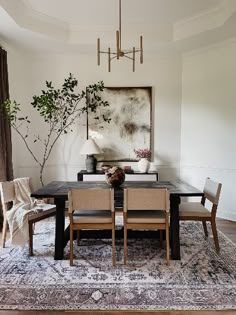 a dining room table with chairs and a painting on the wall in the back ground