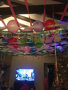 balloons and streamers are hanging from the ceiling in front of a flat screen tv