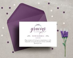 a purple envelope and some flowers on a gray surface with white polka doting around it