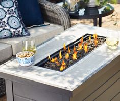 a fire pit sitting on top of a table next to a glass of wine and two glasses of wine