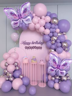 a birthday party with balloons, cake and butterflies on the wall in front of it