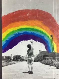 a young boy riding a skateboard down a sidewalk under a rainbow painted over the top of his head