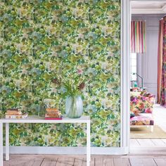 a living room with floral wallpaper and white table in front of the couches