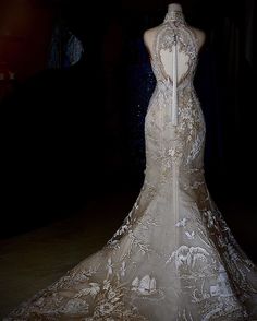 the back of a wedding dress on display in a dark room with other mannequins