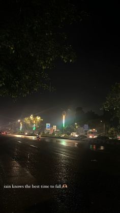 a city street at night with cars driving on the road and traffic lights in the background