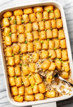 a casserole dish filled with tater tots and green onions