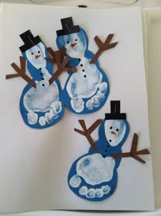 three snowmen made out of paper on a white wall