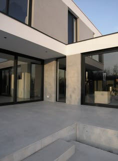 an empty concrete patio with steps leading up to the front door and glass doors on both sides