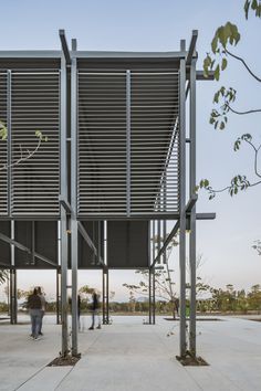 people are walking around in an open area with metal structures on either side of the walkway