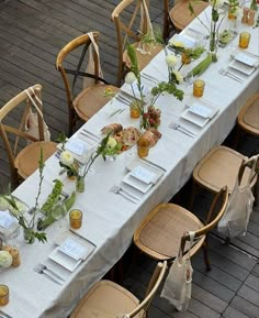 a long table is set up with place settings and flowers on it for an event