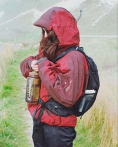 a person with a backpack and water bottle in their hands walking up a path to the top of a hill