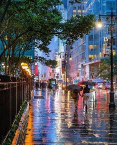 people walking down the street in the rain with umbrellas