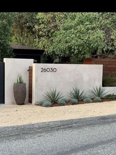 an entrance to a house with plants and trees in the front yard, next to a fence