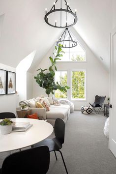 a living room filled with furniture and a white table in front of a large window