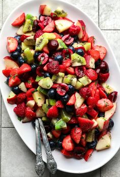 a white plate topped with fruit salad next to a fork