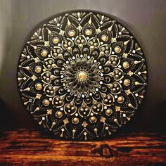 a decorative metal plate sitting on top of a wooden table next to a black wall