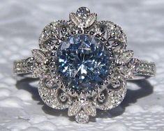 "A beautiful and delicate engagement ring featuring a sparkly light blue sapphire in 14K white gold intricate filigree ring. The center stone is a pretty light blue Ceylon sapphire, measuring 7.2mm diameter and 2.04 carats. The beautiful Portuguese cut and light crystal make it very sparkly (please check the video). It is eye-clean and basic heat only (or might even be untreated). Great choice for an engagement ring! The sapphire is set in a vintage-inspired 14K white gold filigree ring, featuri Elegant Light Blue Sapphire Promise Ring, Elegant Light Blue Brilliant Cut Ring, Light Blue Sapphire Ring With Center Stone For Wedding, Wedding Light Blue Sapphire Ring With Center Stone, Elegant Sapphire Filigree Wedding Ring, Elegant Light Blue Jewelry With Center Stone, Heirloom Blue Filigree Ring For Weddings, Elegant Sapphire Ring With Intricate Design, Elegant Light Blue Wedding Ring