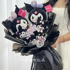 a woman is holding a bouquet of black and white flowers in her hands with pink bows