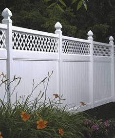 a white fence with flowers in the foreground