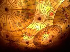 several umbrellas lit up in the dark with yellow lights shining down on them and flowers all over them