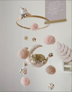 a baby mobile with pink pom poms hanging from it's side and a bird sitting on top of the moon