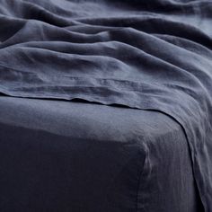 an unmade bed with dark blue sheets