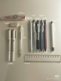 several different pens and pencils are lined up next to a ruler