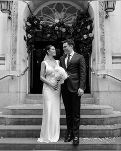 a bride and groom standing on steps in front of a building