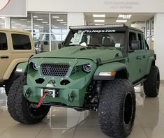 a green jeep is parked in a showroom