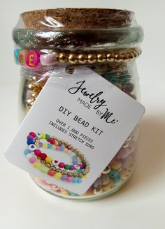 a jar filled with lots of beads and a tag that says jewelry made easy diy bead kit